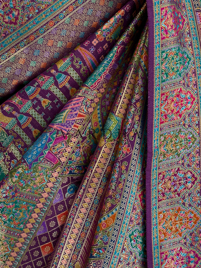 Colorful patterned fabric with intricate designs Macro texture shot of a premium deep purple Meenakari silk saree in gathered pleats, detailing the multi-colored woven diamond lattice, traditional Indian doll motifs, and rich heritage weaving techniques.