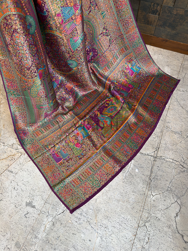 Colorful patterned fabric draped over a chair on a stone floor Trailing edge of a majestic purple festive saree displayed on a stone floor, revealing a heavily woven pallu with intricate royal court figures, traditional Indian motifs, and elaborate multi-colored floral borders.