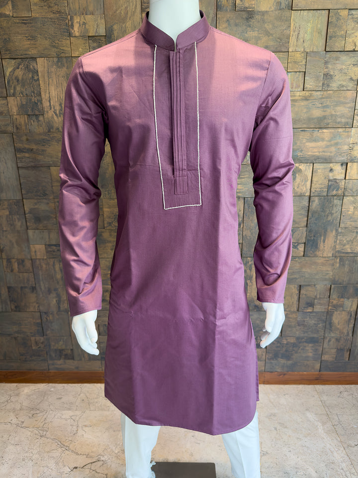 Mauve kurta on a mannequin against a wooden paneled wall. Premium breathable Wine cotton kurta for men, featuring a smooth crisp finish and meticulously structured formal detailing.
