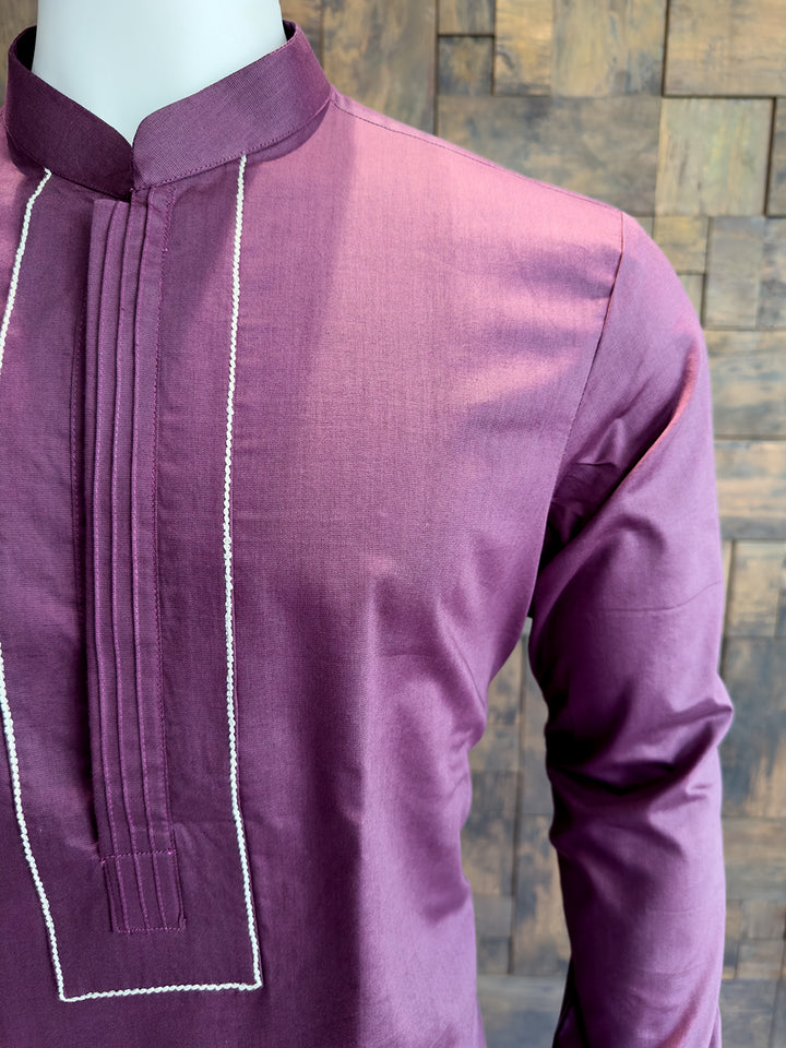 Purple kurta with white embroidery on a mannequin against a wooden panel background. Detailed view of a Wine-colored kurta chest featuring center vertical pintucks and a formal contrast stitched frame for a tailored edge.