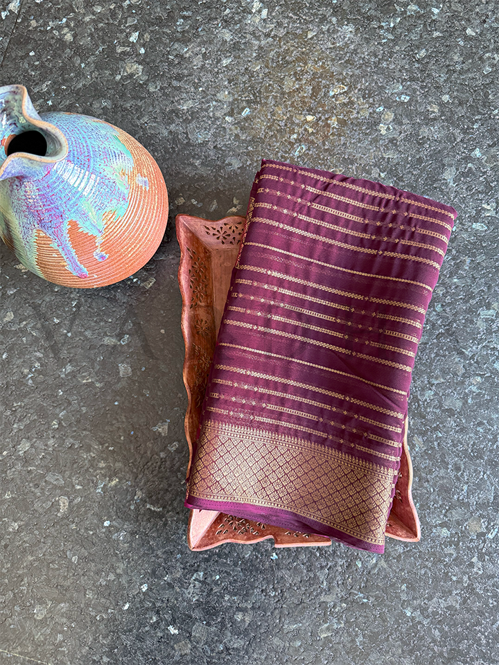 Folded wine georgette saree with zari stripes and intricate diamond weave border, ideal for light festive occasions