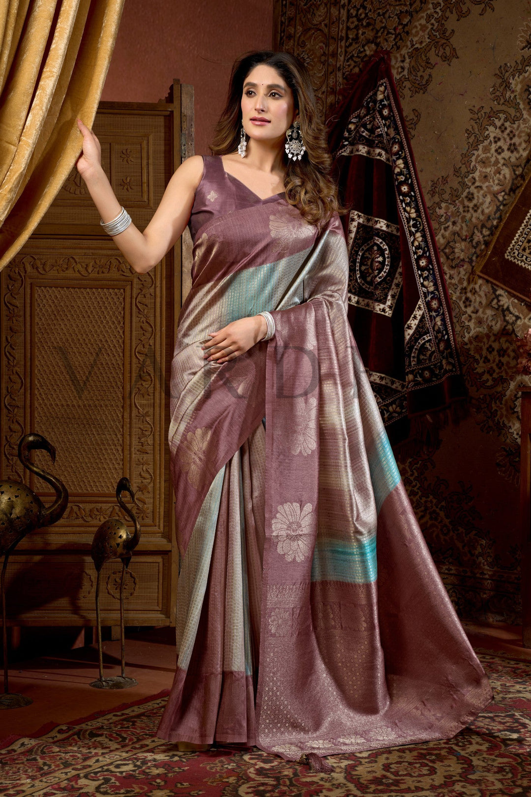 Woman in a traditional saree standing in an ornate room. Wine Prijam Kota Silk Saree with Woven Floral Zari Work-StellaEnjoy premium add-ons including Pre-drape Services, Custom Stitched Blouse at a Complimentary Price, Fall and Edging, Gift Packaging, and Free Shipping!