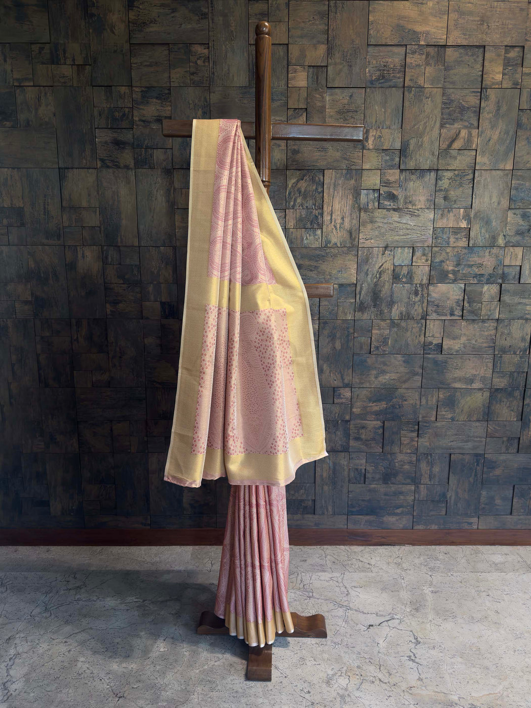 Traditional outfit with a yellow dupatta and pink skirt against a textured wall.