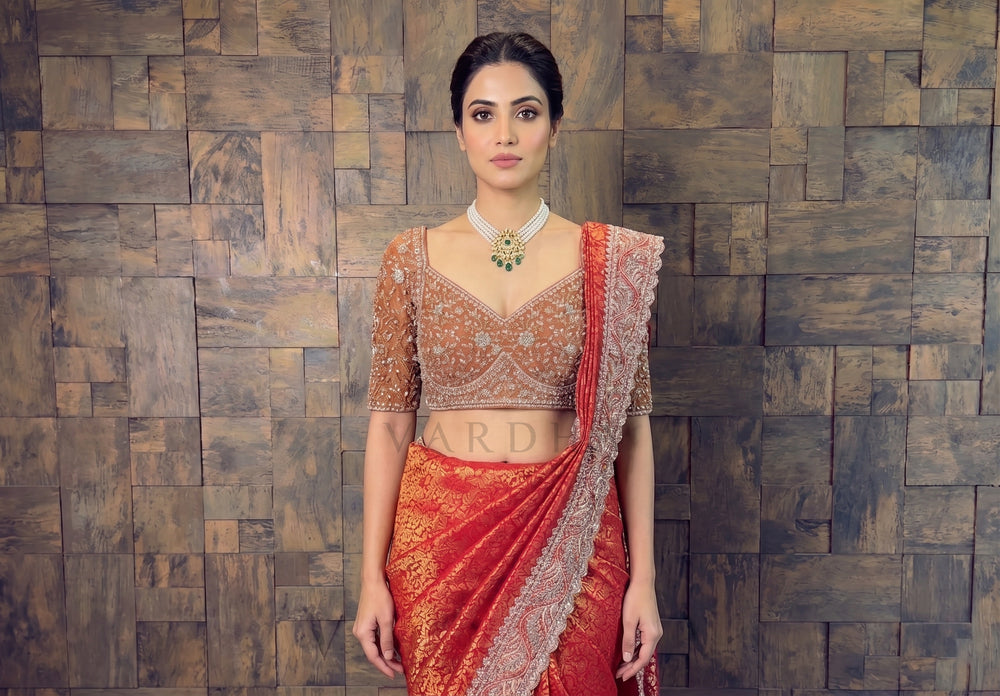 Woman in traditional outfit standing against a wooden paneled wall