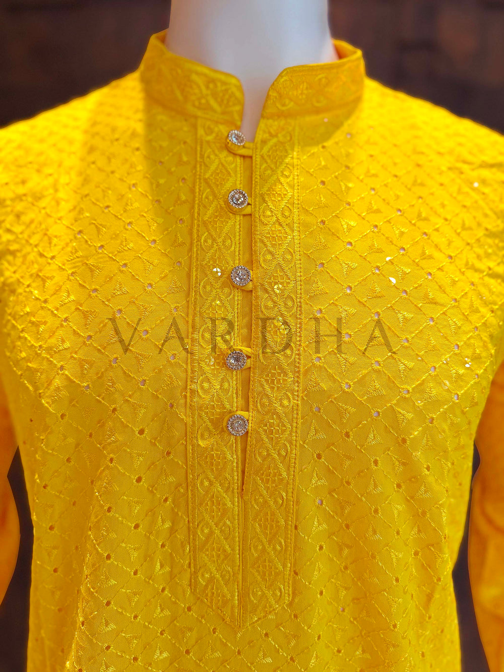 Yellow embroidered kurta on a mannequin with 'Vardha' branding. Close-up of yellow kurta neckline showing patterned band collar, jeweled button placket and textured jacquard diamonds accented by micro sequins.