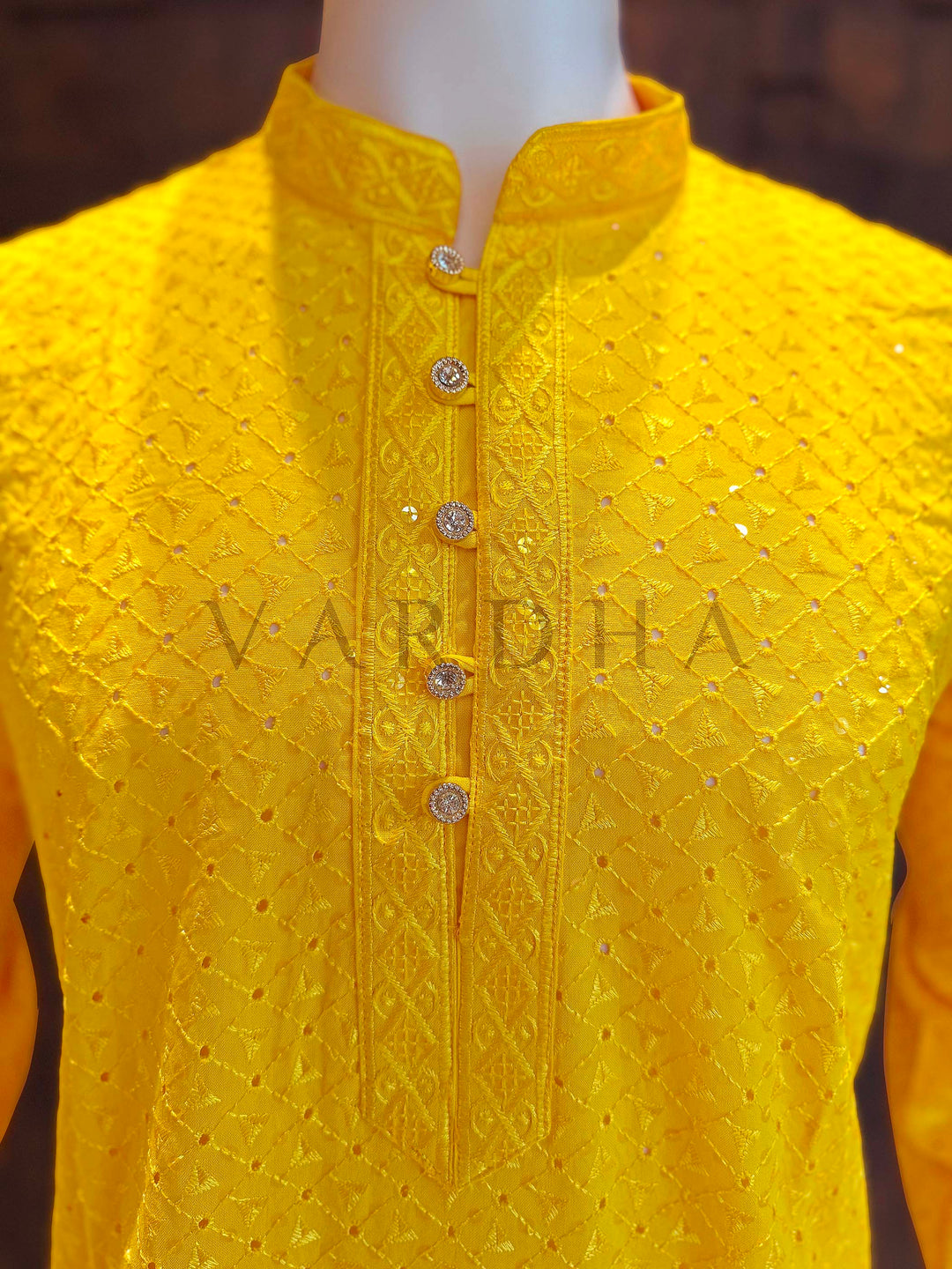Yellow embroidered kurta on a mannequin with 'Vardha' branding. Close-up of yellow kurta neckline showing patterned band collar, jeweled button placket and textured jacquard diamonds accented by micro sequins.