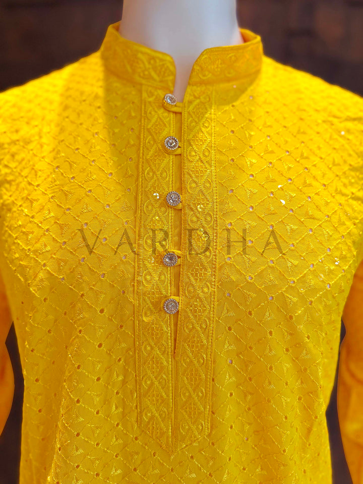 Yellow embroidered kurta on a mannequin with 'Vardha' branding. Close-up of yellow kurta neckline showing patterned band collar, jeweled button placket and textured jacquard diamonds accented by micro sequins.