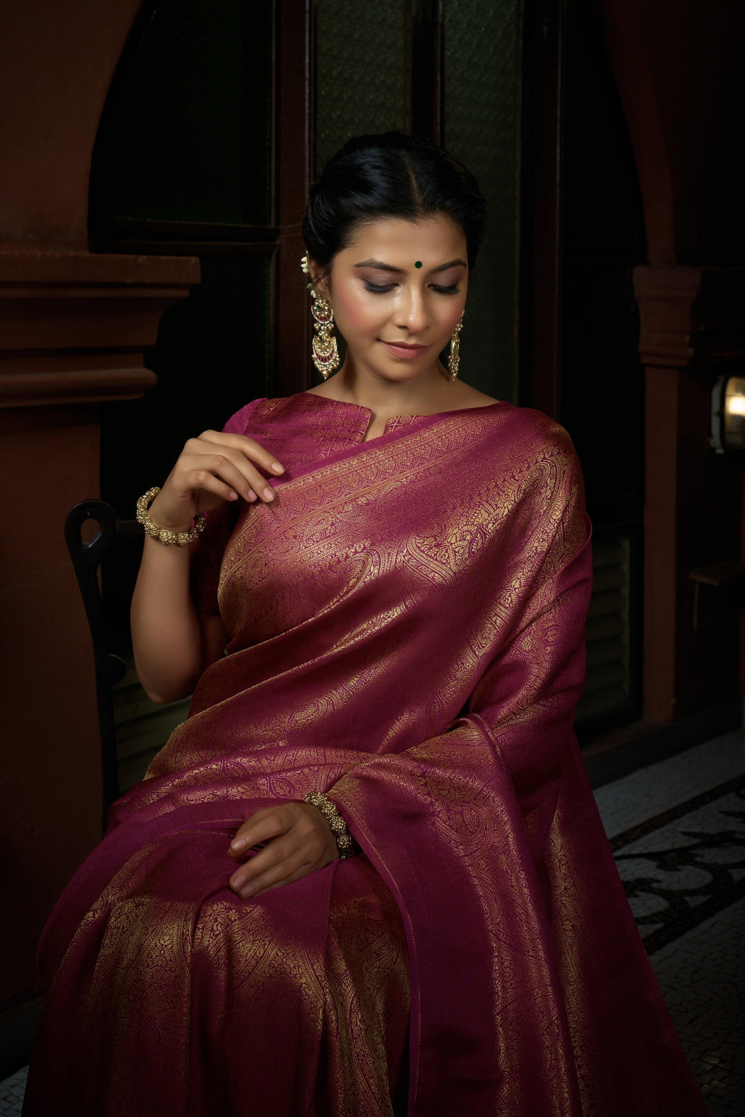 Close-up of zari weaving on the pink silk fabric, showcasing intricate golden patterns.