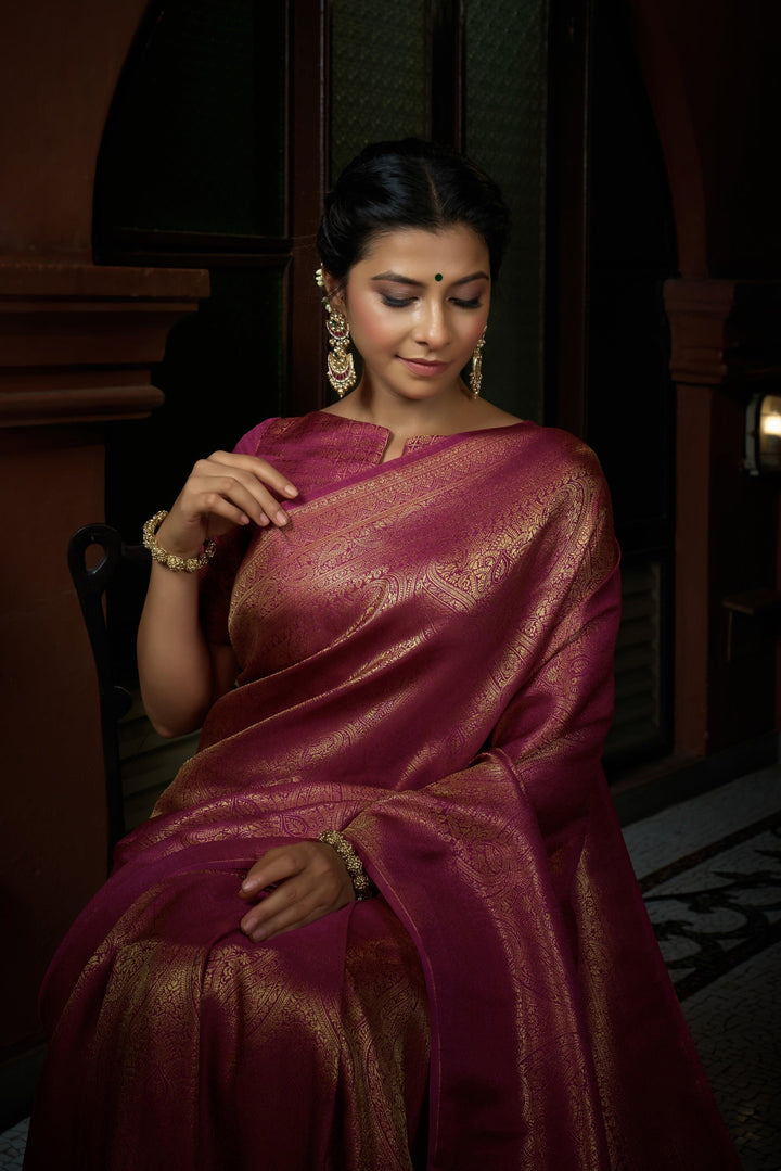 Close-up of zari weaving on the pink silk fabric, showcasing intricate golden patterns.