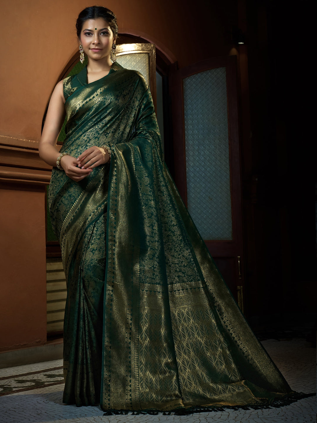 Model draped in Brunswick Green Kanjeevaram Silk Saree with golden zari work, front-facing with pleated drape.