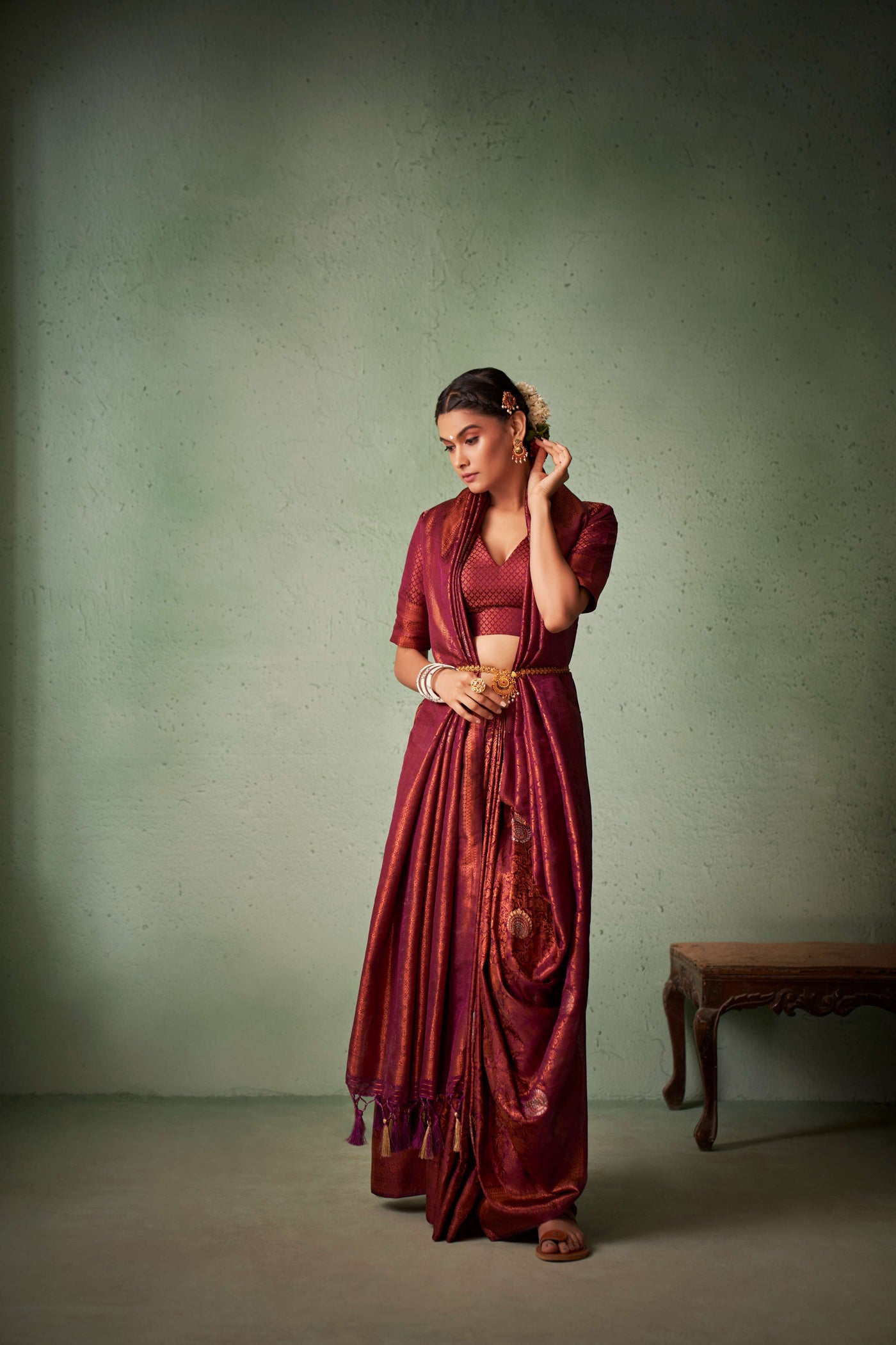 Model wearing maroon silk saree styled with gold jewelry.