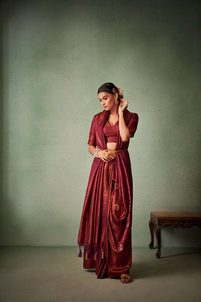 Model wearing maroon silk saree styled with gold jewelry.