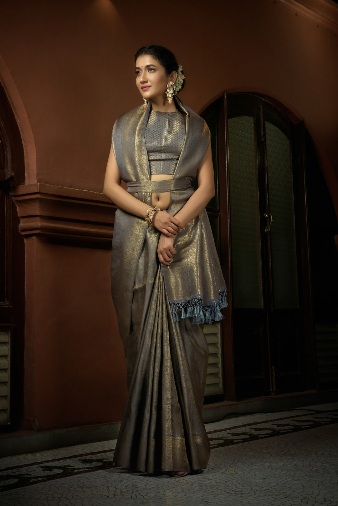 Model wearing Platinum Grey Kanjeevaram Silk Saree with golden zari work, full front view with elegant pleats.