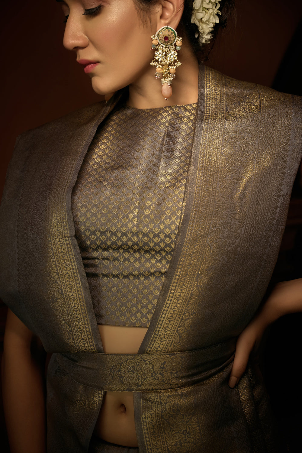 Close-up of floral-inspired golden zari motifs on the platinum grey silk fabric.