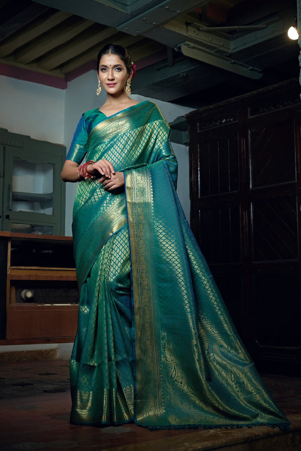 Full saree flat lay highlighting the teal blue hue and traditional detailing.