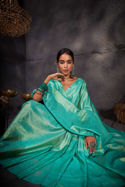 Model draped in turquoise blue Kanjeevaram saree with shimmering gold zari work.